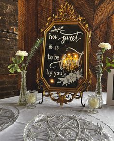 a table topped with vases filled with flowers and a framed sign that says, he has sweet it is to be by you