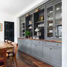 a large kitchen with gray cabinets and wooden flooring, along with a dining room table