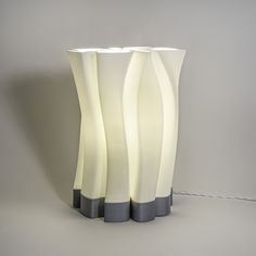 three tall white vases sitting next to each other on a gray surface with wires running through them