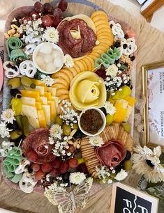 a platter filled with lots of different types of cheese and meats on top of a table