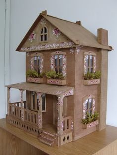 a paper doll house sitting on top of a wooden table next to a white wall