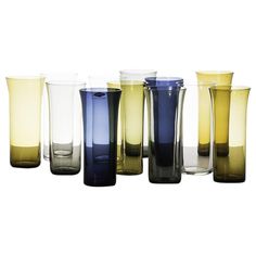 several different colored glass vases lined up in a row on a white background,