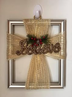 a decorative cross with the word believe hanging on it's side in front of a white wall