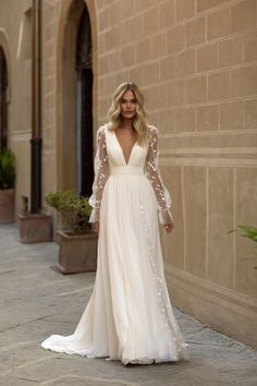 a woman in a wedding dress standing on the sidewalk