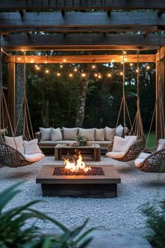 a fire pit in the middle of a patio with hanging chairs and lights above it