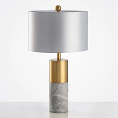 a table lamp with a marble base and gold trim around the top, on a white surface