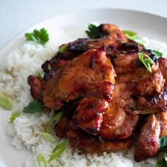 a white plate topped with rice and meat next to cilantro leaves on top of it