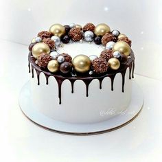 a white cake with chocolate and gold decorations on it's icing drips