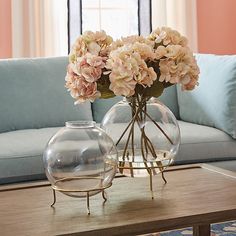 two vases filled with flowers sit on a coffee table in front of a couch