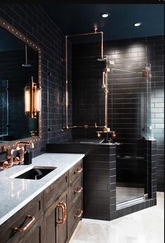 a bathroom with black tiles and gold fixtures on the walls, along with a marble countertop