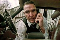 a man sitting in the driver's seat of a car talking on a cell phone