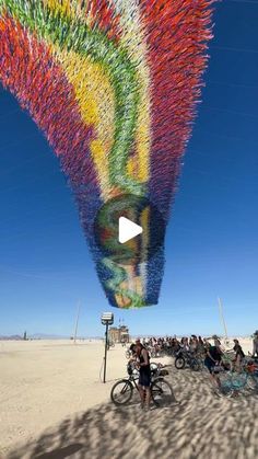 a large multicolored kite is being flown in the air over people on bicycles