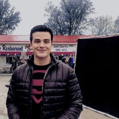 a man standing in front of a restaurant with his arms crossed and smiling at the camera