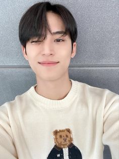 a young man wearing a sweater with a bear on it