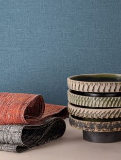 a stack of bowls sitting next to each other on top of a table covered in fabric