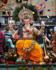 an elephant statue is adorned with feathers and confetti as it sits on the ground