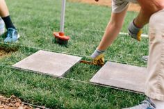 two men are working on some concrete in the grass