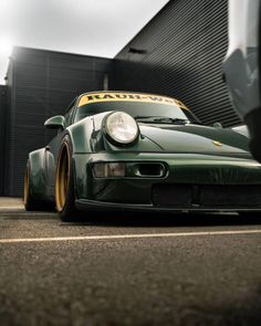 a green sports car parked in front of a building with yellow lettering on the side