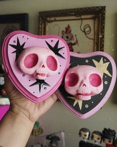 someone is holding up two pink and black heart shaped items in their hand, with one skull on the other side