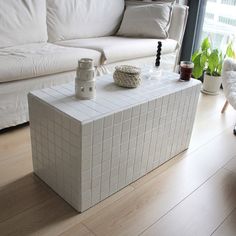 a white couch sitting next to a table on top of a hard wood floor in front of a window