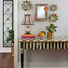 a table topped with a lamp next to a mirror and vase filled with oranges