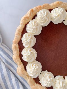 a chocolate pie topped with whipped cream on top of a blue and white striped napkin