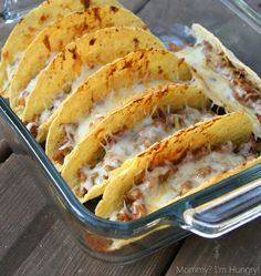 several tacos in a glass dish with cheese and sauce on top, ready to be eaten