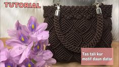 a crocheted purse with purple flowers in the foreground and text that reads, tas tali kur motif daun ata