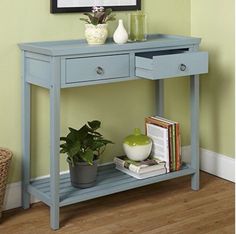 a blue console table with books and plants on top