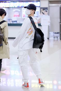 two people wearing masks and backpacks at an airport