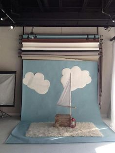 a photo studio with a blue backdrop and white clouds on the wall, including a sailboat