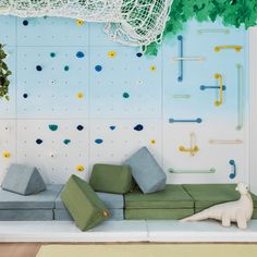 an indoor climbing wall with green and gray cushions