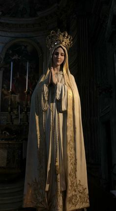 a woman dressed in white and gold with a crown on her head standing next to a statue