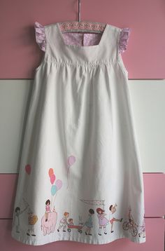 a white dress hanging on a pink and white striped wall with children's drawings