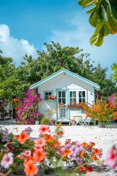 a small white house surrounded by flowers and trees