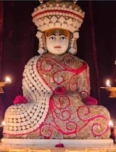 a buddha statue sitting on top of a table with candles in front of it's face