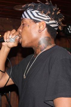 a man with dreadlocks on his head singing into a microphone