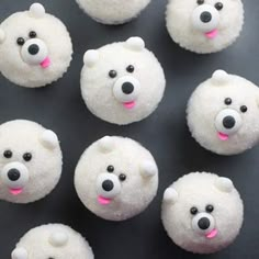 twelve polar bear mini cupcakes on a black surface with pink and white frosting