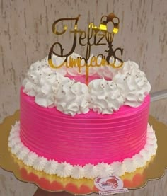 there is a pink and white cake with gold lettering on top that says feliz cumpreos