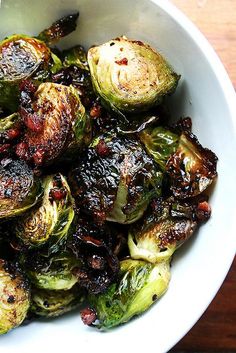 a white bowl filled with brussel sprouts on top of a wooden table