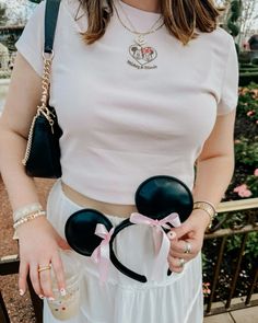 a woman wearing minnie mouse ears and holding a cup