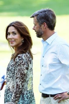 a man and woman standing next to each other in front of a green grass covered field