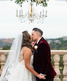 a bride and groom kissing in front of a chandelier at their wedding ceremony