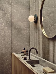 a bathroom sink sitting under a mirror next to a wall mounted faucet