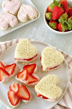 there is a plate with sandwiches and strawberries next to the plates on the table