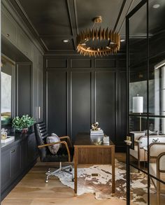 a living room with black walls and wood flooring, an office desk and chair