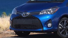 the front end of a blue toyota car parked on a road next to some water