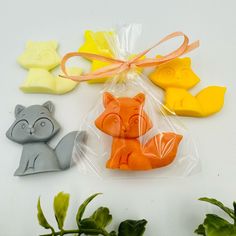 four rubber animals in plastic bags sitting next to each other on top of leaves and plants