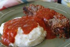 meatloaf with mashed potatoes and sauce on a green plate, ready to be eaten