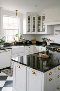 a kitchen with white cabinets and black counter tops, gold pulls on the cabinet doors